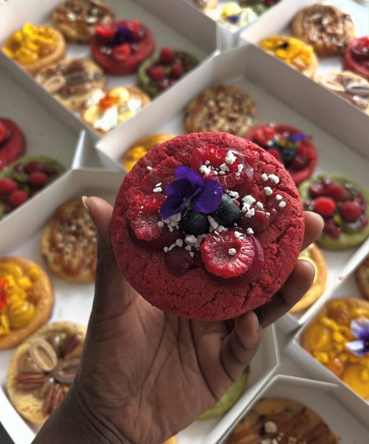 Cookie red velvet garni de framboises, myrtilles et d'une pensée
